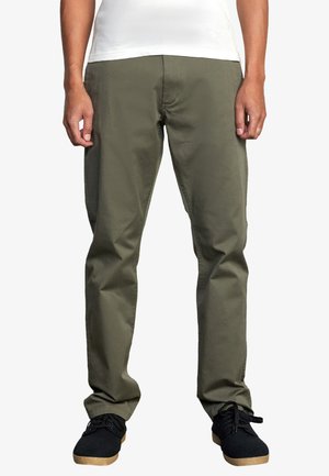 Pantalons droits en vert olive en tissu mélangé de coton, avec poches avant et taille propre, associés à des baskets noires.