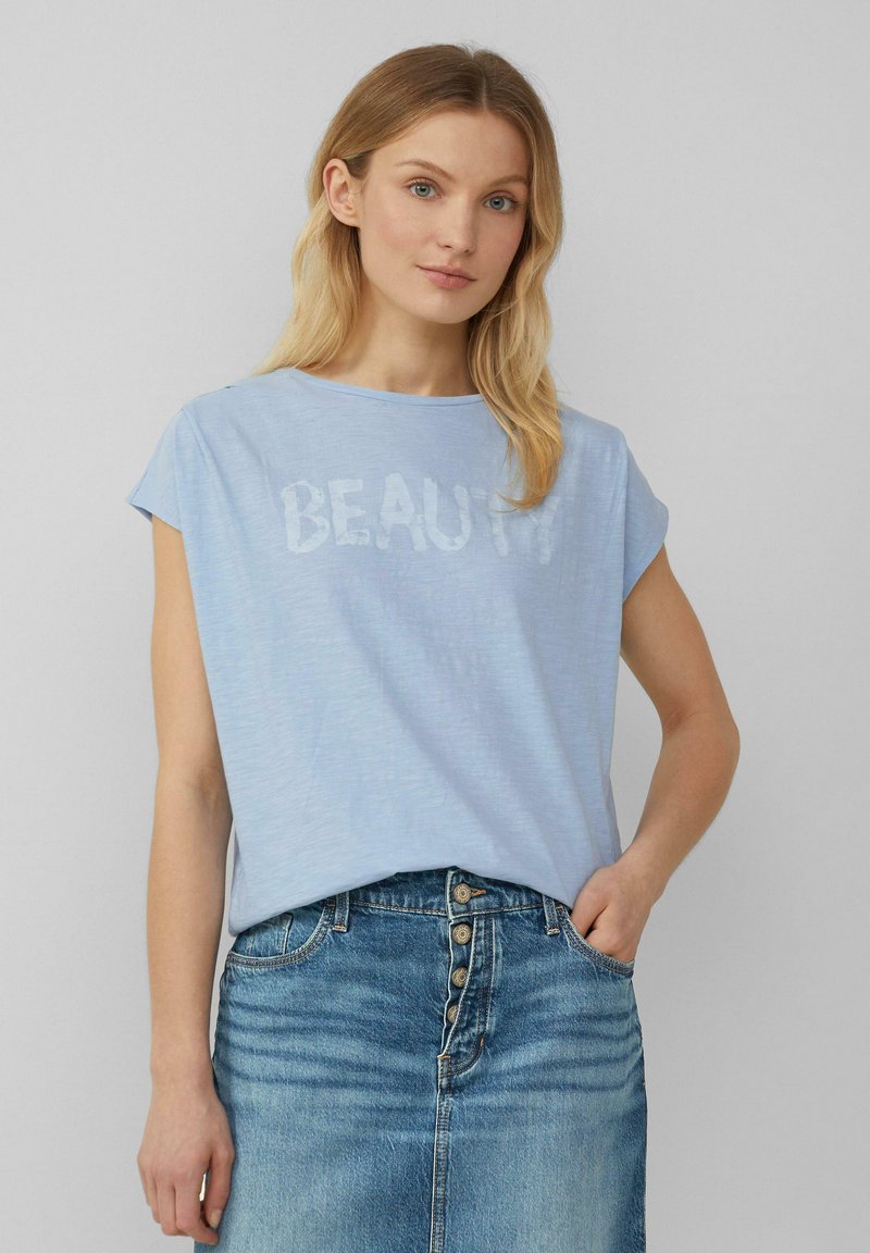 Lichtblauwe t-shirt met korte mouwen met "BEAUTY" in een subtiel patroon. Zachte, lichte stof gecombineerd met een denim rok.