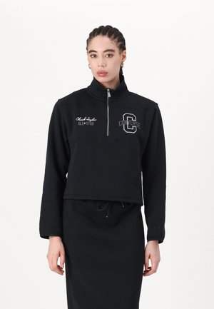 Sudadera recortada negra con cremallera y cuello alto, que presenta el logo blanco de "Converse" y el bordado de "Chuck Taylor ALL*STAR" en la parte delantera.