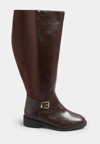 Brun läderknästövel med ett strukturerat meshpanel, guldfärgad spänne och låg klack. Slät yta och strömlinjeformad design.