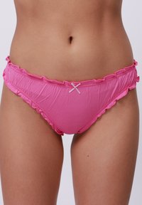 Roze katoenen bikinionderdeel met gekruiste randjes en een kleine witte strikaccent aan de voorkant. Zachte textuur, minimalistische bedekkingsontwerp.