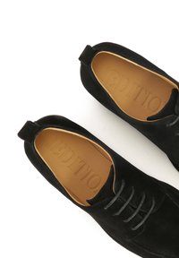 Chaussures en suede noir avec une forme lisse et arrondie. Dotées d'une pointe simple, de lacets noirs et d'une semelle intérieure en cuir beige estampillée "EDITIO."