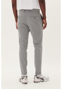 Grå skräddarsydda byxor med en slät textur, med bakfickor med knäppning, ihopparade med sportskor i silver och flerfärgade accenter.