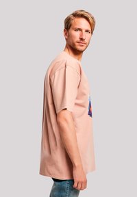 Light pink cotton t-shirt with short sleeves, featuring a multicolored graphic design on the front. Casual fit, smooth texture.