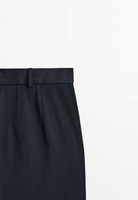 Pantalons navy à rayures fines avec une taille plate, passants de ceinture et deux poches avant. Fabriqués dans un tissu texturé avec des rayures verticales.