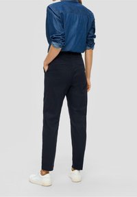 Námořnické modré kalhoty vyrobené z bavlněné směsi, s úzkým střihem, bočními kapsami a čistým designem, ve spojení s džínovou košilí.