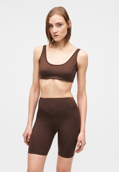 Barna sportos szett, amely egy scoop nyakú sportmelltartóból és magas derekú rövidnadrágból áll. Simább, rugalmas anyag kontrasztos varrással.
