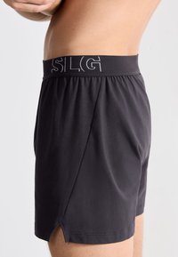 Boxer neri con vita elastica che presenta il marchio "SLG". Il tessuto è morbido e dotato di fessure laterali per il comfort e la libertà di movimento.