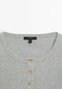 Haut en maille côtelée gris clair avec col rond et trois boutons beiges sur le devant, taille petite.