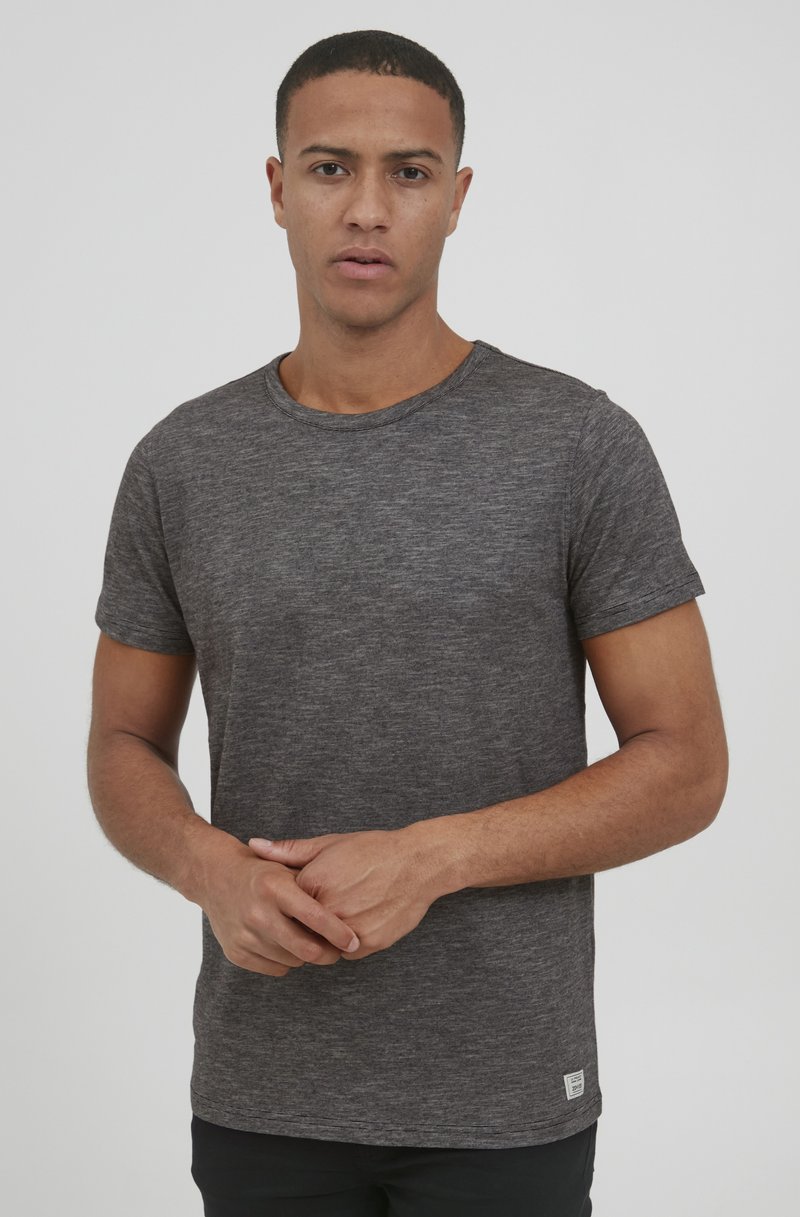 Camiseta de manga corta y cuello redondo en un tejido texturizado de color gris oscuro. Presenta un corte relajado y una pequeña etiqueta de la marca en el dobladillo.