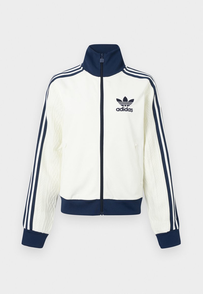 White athletic jacket with a navy collar and cuffs, features three navy stripes along each arm, and an embossed texture on the sleeves.