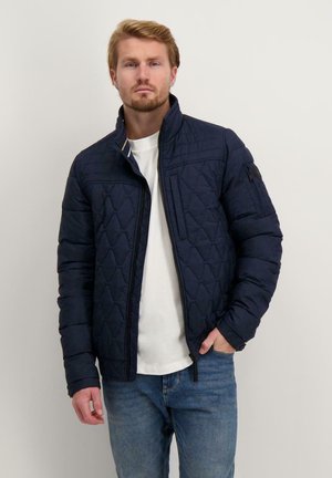 Marine blauwe gewatteerde jas met een staande kraag, ritssluiting en een hexagonaal patroon. Voorzien van zijzakken en een merklabel op de mouw.