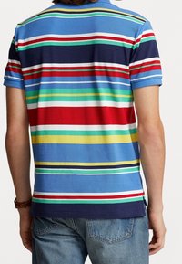 Randig polo t-shirt med blå bakgrund, med horisontella ränder i röd, grön, gul och vit. Korta ärmar och avkopplad passform.