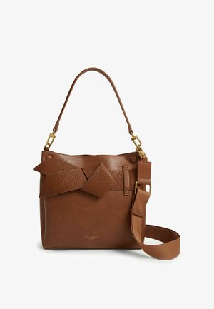 Sac à main en cuir marron avec un nœud décoratif texturé, une poignée courte et une large bandoulière réglable avec des finitions dorées.