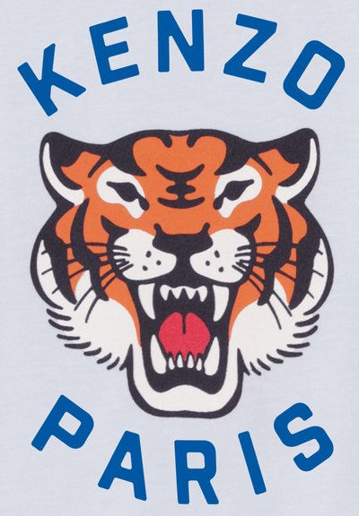Tissu blanc présentant un graphisme d'un tigre orange rugissant avec des accents noirs, accompagné de "KENZO" et "PARIS" en texte bleu gras.