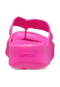 Roze rubberen sandalen met een dikke zool en een ontwerp met één bandje. Bevat een reliëflogo "CROCS" en heeft een gladde, matte structuur.
