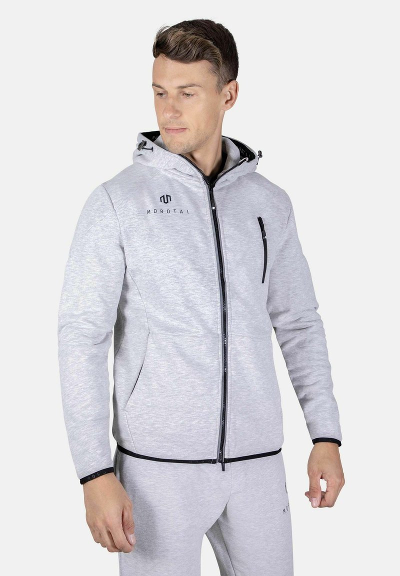 Haut de sweatshirt zippé gris clair avec une fermeture éclair noire, deux poches latérales et une capuche avec cordon de serrage. Présente le logo 'Morotai' sur la poitrine.