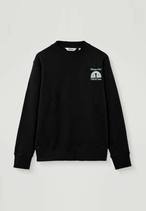 Zwarte crewneck-trui met lange mouwen, kleine witte tekst en logo "Ellesse 1959 Club di Corsa" op de linkerbovenzijde van de borst.