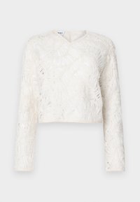 Vit beskuren topp med långa ärmar, V-halsringning, texturerad tyg med bladmönster och en subtil genomskinlig uppenbarelse.
