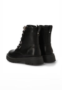 Botas de tobillo de cuero negro con un acabado texturizado, que presentan un sistema de cordones en la parte delantera, cremalleras laterales y suelas de goma gruesa.