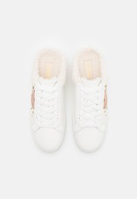 Weiße Sneaker mit einem kuscheligen, cremefarbenen Futter, vorderem Schnürsenkel und einem dekorativen goldenen Akzent an der Seite. Glatte Lederausführung.