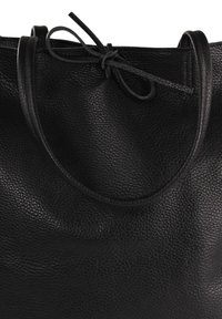 Sac fourre-tout en cuir noir avec une surface texturée, une forme douce et arrondie, et deux poignées. Il dispose d'une fermeture par lien en haut.