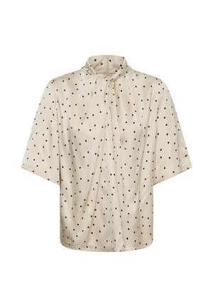 Bluza bej cu mâneci scurte, cu buline negre, guler înalt și detaliu plisat în față.