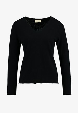 Camiseta negra de manga larga con escote en V, hecha de una tela suave. Presenta un corte holgado con un dobladillo ligeramente deshilachado y un interior del cuello texturizado.