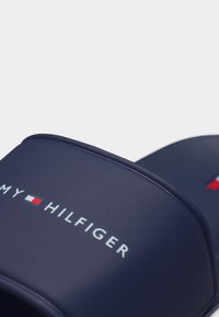 Σανδάλια slide Tommy Hilfiger σε ναυτικό μπλε με λευκό κείμενο λογότυπου και σήμα σημαίας σε κόκκινο, λευκό και μπλε στο λουράκι.