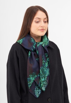 Foulard in seta con motivo astratto blu scuro e verde, legato attorno al collo, con una texture liscia e una forma fluida.
