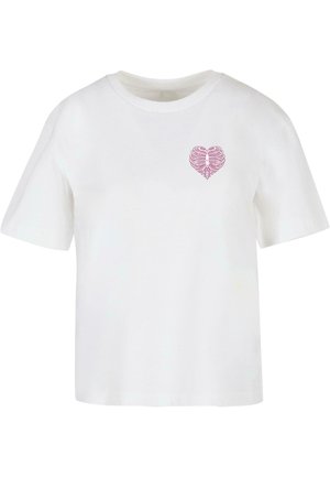 T-shirt bianco in cotone con un design a cuore a forma di gabbia toracica rosa sul lato sinistro del petto, con maniche corte e scollo rotondo.