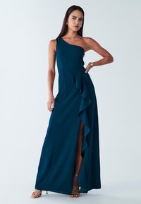 Ein ärmelloses, bodenlanges Kleid aus tiefem Teal-Stoff mit einer seitlichen Rüsche und einem Schlitz. Es hat ein tailliertes Oberteil und eine glatte Textur.