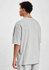 Jasnoszary,oversized t-shirt z krótkim rękawem wykonany z miękkiej bawełny, z okrągłym dekoltem i luźnym krojem oraz prostym wykończeniem dołu.