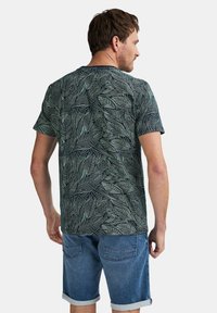 Kortærmet marineblå t-shirt med et grønt bladmønster, lavet af blødt stof, parret med denimshorts med opfoldede manchetter.