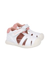 Sandalias infantiles blancas y rosas con diseño recortado, tira de Velcro y suela de goma texturizada. Decoradas con patrones florales.