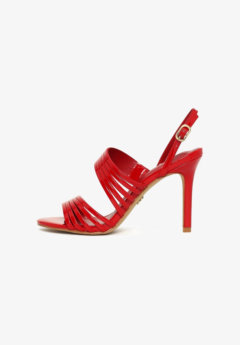 Sandalia de tacón alto en charol rojo con varias tiras delgadas sobre el pie, punta abierta y tiras ajustables en el tobillo con hebilla dorada.