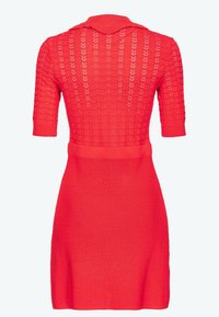 Robe rouge en tricot avec un motif texturé, manches courtes et col. La jupe est ajustée et s'évase vers l'ourlet.