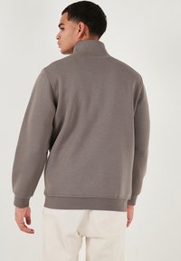 Hall pullover jope hallikaelusega, soonikkoes varrukate ja äärega. Pehme tekstuur, lõdvestatud istuvus ja õmbluse detailid seljal.