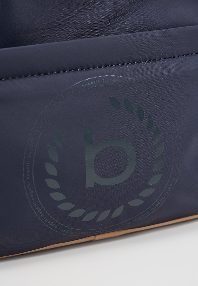 Un sac en tissu bleu marine avec une texture lisse, présentant un grand logo en relief au centre, accentué par un panneau inférieur beige.