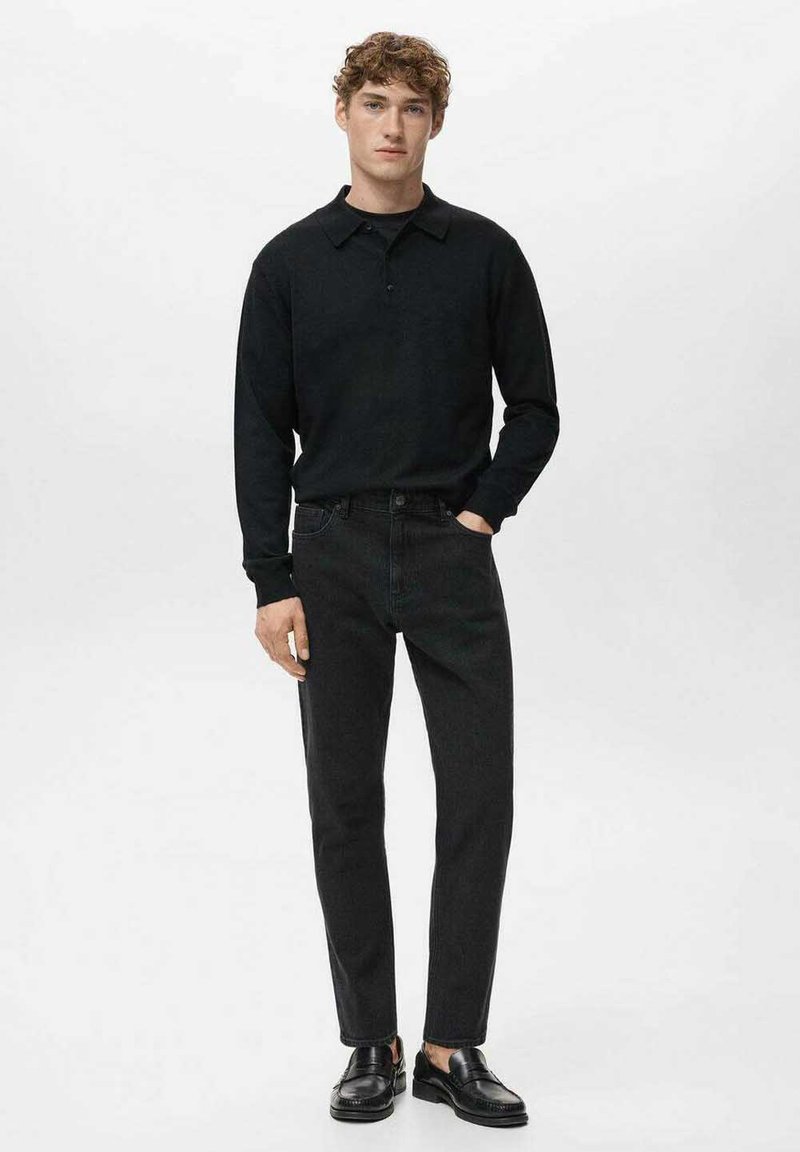 Polo à manches longues noir, col boutonné, associé à un jean foncé et des chaussures noires. Design simple avec une silhouette cintrée.