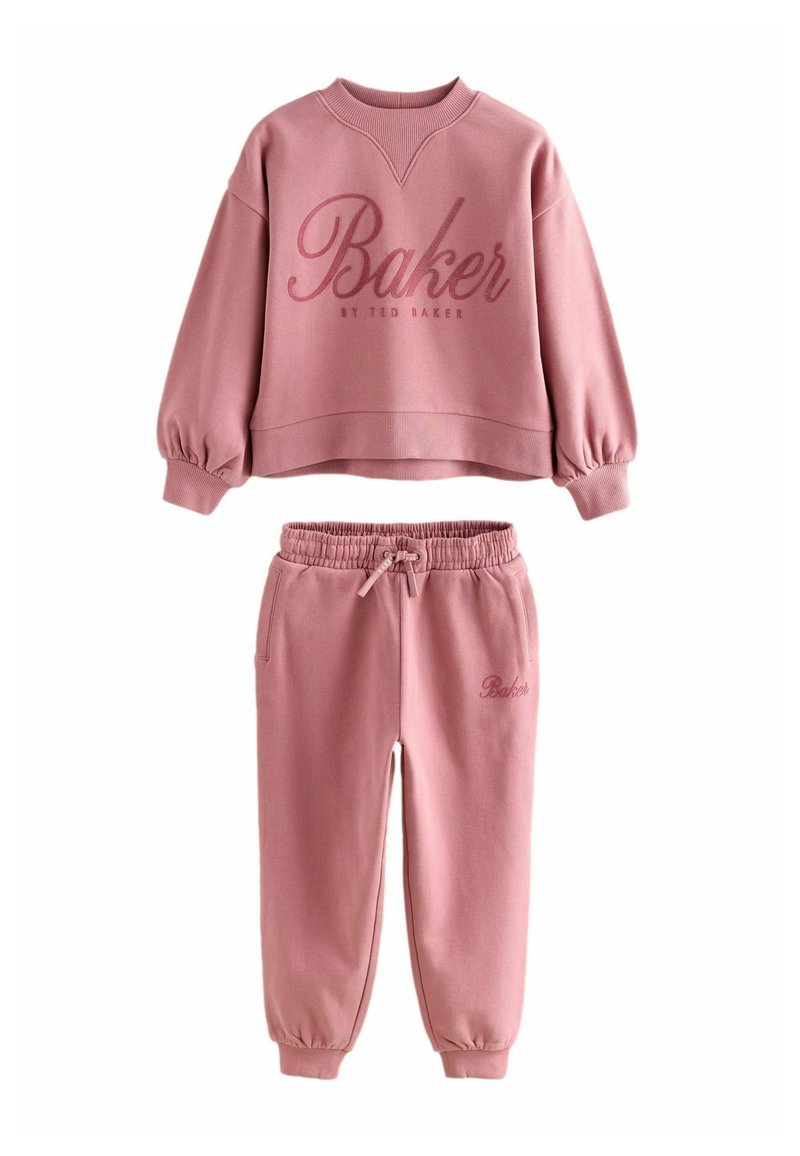 Rožinė sportinė palaidinė ir kelnių komplektas su "Baker by Ted Baker" ženklu, kuris turi elastinius rankogalius ir liemenį, o kelnių juostoje yra raištelis.