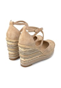 Beżowe zamszowe sandały na koturnie z krzyżującym się paskiem na kostce i teksturowanymi, plecionymi detalami z liny na obcasie. Udekorowane metaliczną nitką.