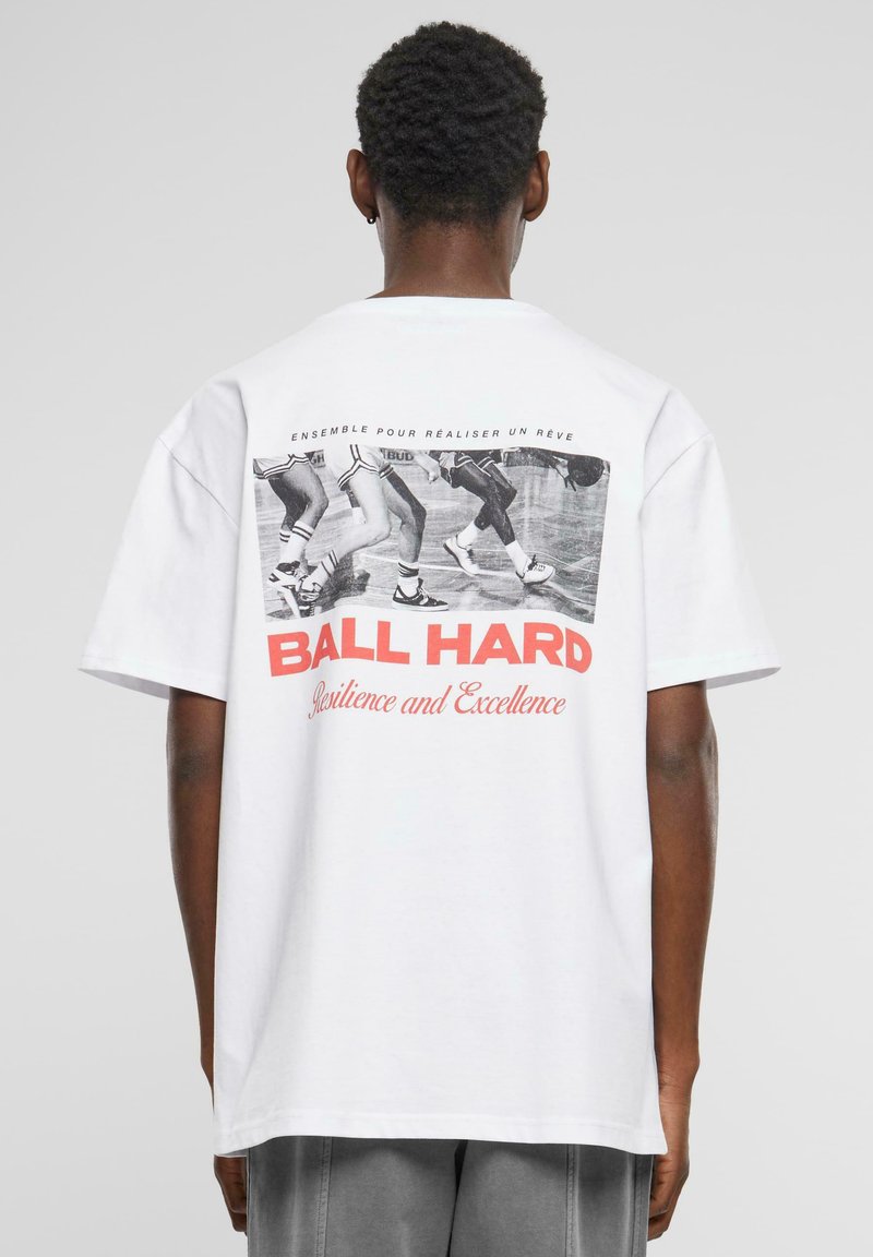 T-shirt en coton blanc avec une impression graphique au dos, portant le texte "BALL HARD" en rouge, et des danseurs dans une photo en noir et blanc au-dessus.