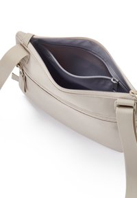 Beige ramenní taška z látky s dvojitými zipovými kapsami a texturovaným povrchem. Interiér má tmavé podšívku a další oddíl pro organizaci.
