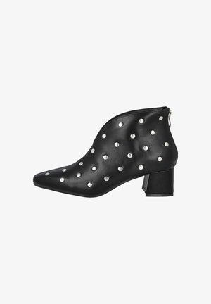 Botines negros de material sintético, con detalles de tachuelas plateadas, punta puntiaguda y tacón grueso con cierre de cremallera.