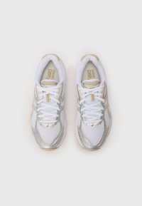 Valged spordijalatsid, millel on võrgu pealispind, hõbedased aktsendid ja heledat beeži detailid. Omab ümaraid paelu ja pehmendatud kaelaosa.