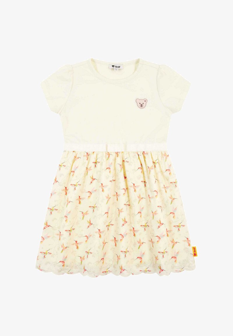 Kurzärmeliges Kleid mit einem cremefarbenen Oberteil und einem hellgelben Rock im Blumenmuster; mit einem Bärenapplikation auf der Brust und einem gewellten Saum.