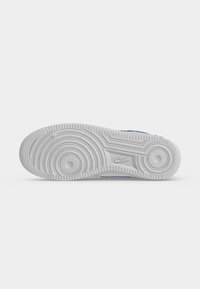 Λευκή σόλα παπουτσιού Nike με κυκλικά σχέδια πέλματος και ορατό λογότυπο Nike στο κέντρο σε λευκό φόντο.