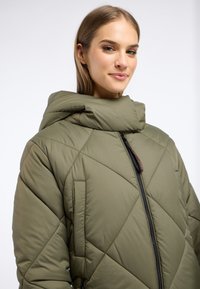 Olijfgroene gewatteerde jas met hoge kraag, diagonale quiltpatroon, ritssluiting aan de voorkant en zijzakken. Glad textuur en casual ontwerp.