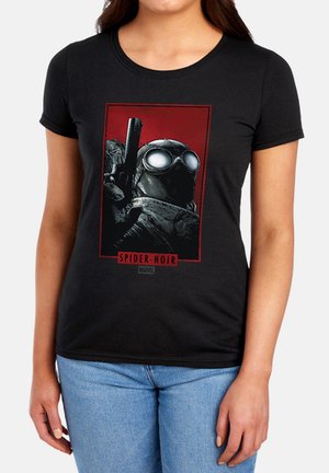 Person trägt ein schwarzes T-Shirt mit Spider-Man Noir-Grafik, die eine maskierte Figur mit Schutzbrille zeigt, die eine Waffe vor rotem Hintergrund hält.